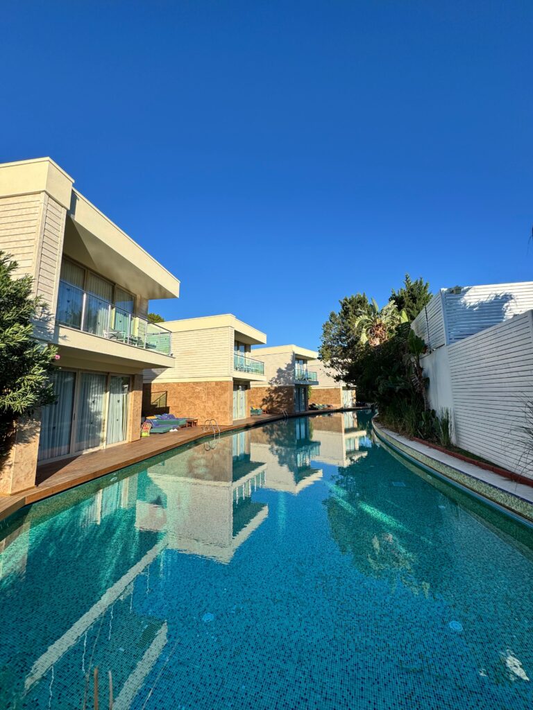 Contemporary villas surrounding a serene outdoor pool under clear blue skies.